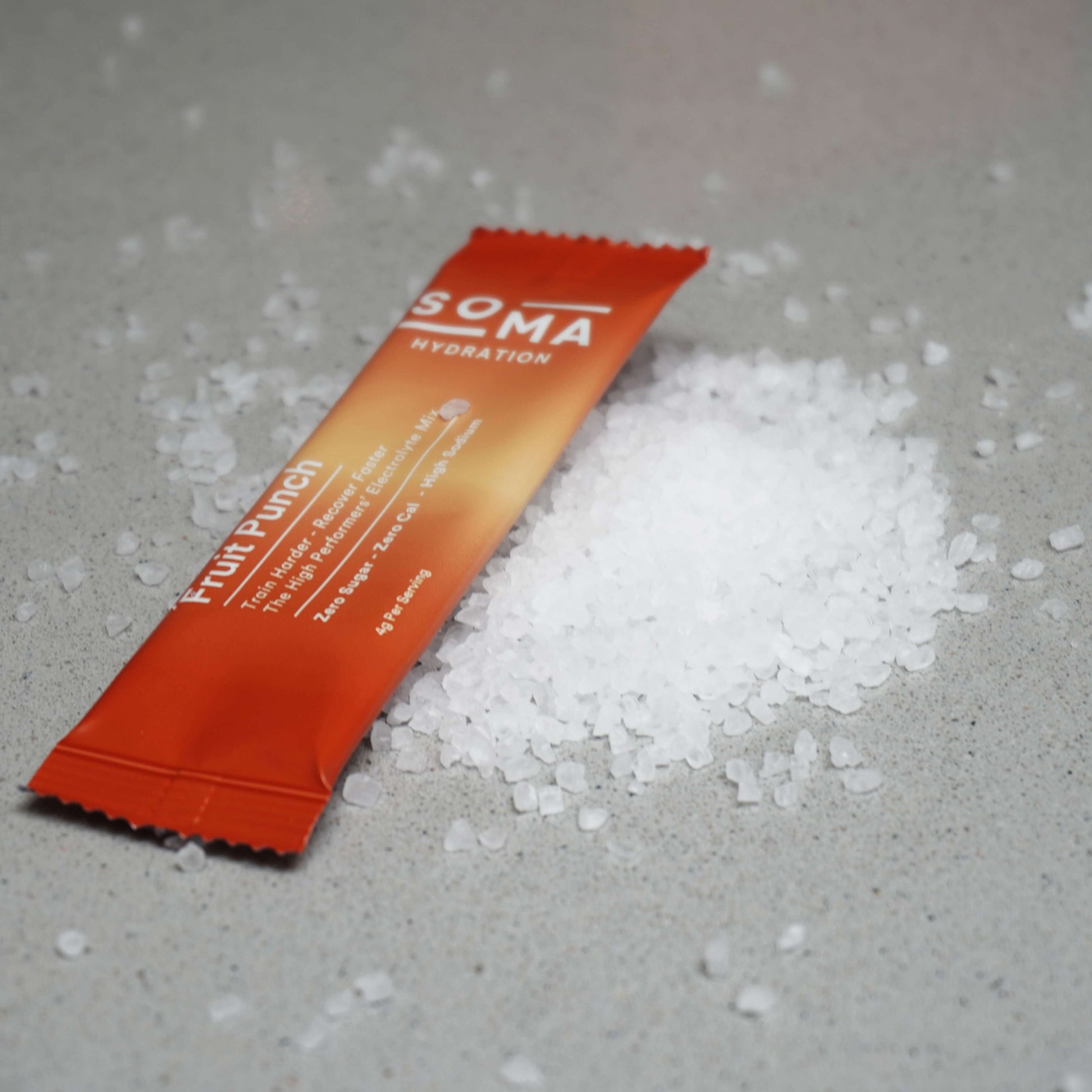 SOMA electrolyte powder sachets displayed on a clean grey background with pile of salt.